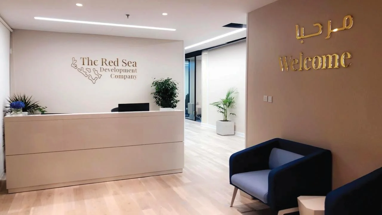 Reception desk with The Red Sea identity and a bilingual welcome sign.