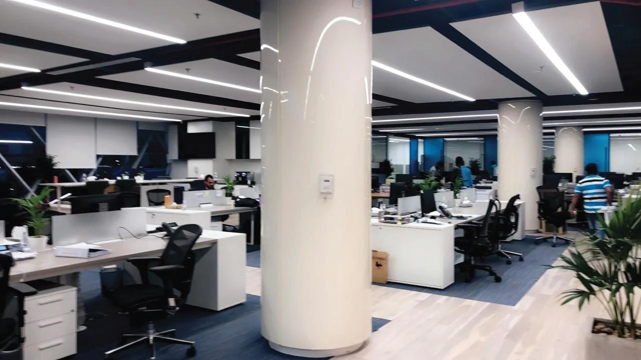 Open office with desks around white columns and blue accent furnishings.