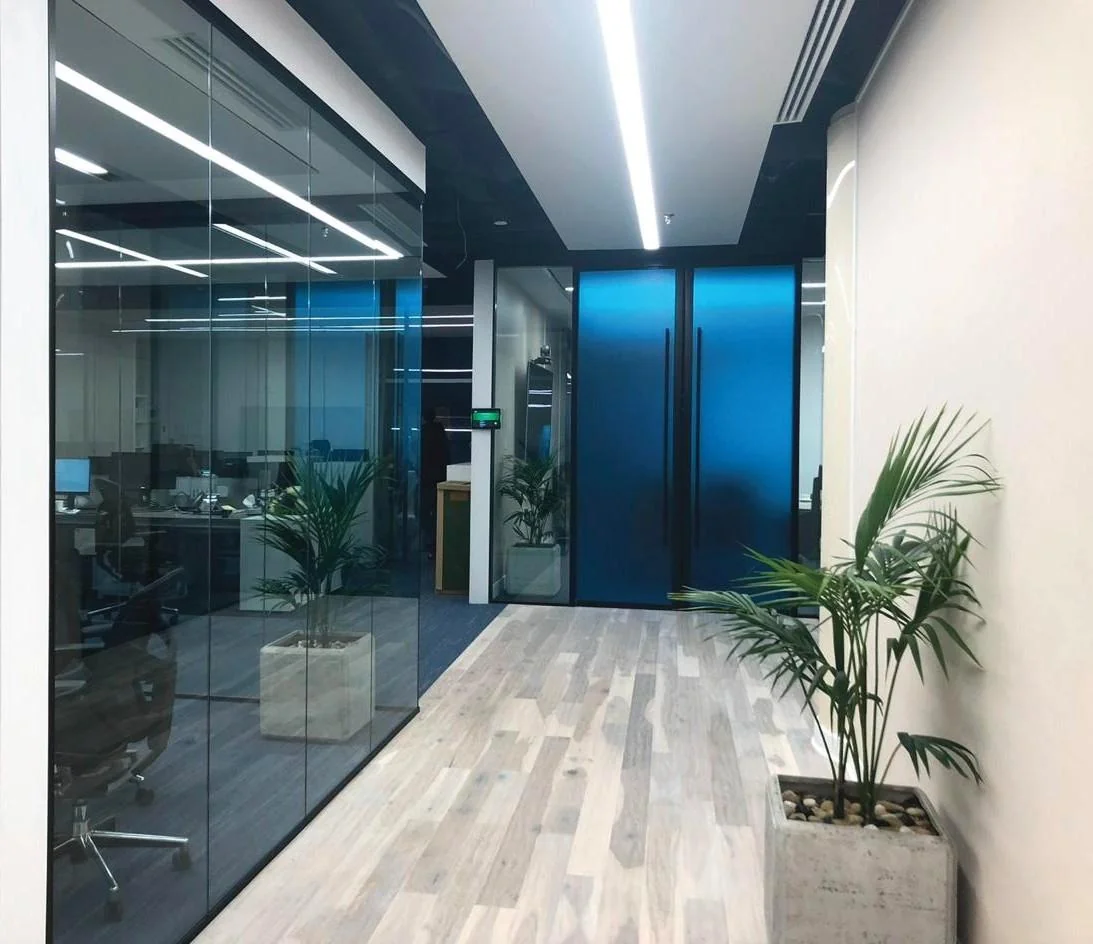 Corridor beside glazed rooms with timber-effect flooring.